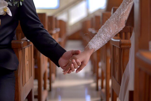 La mi-section des mains d'un couple sur la balustrade de l'église