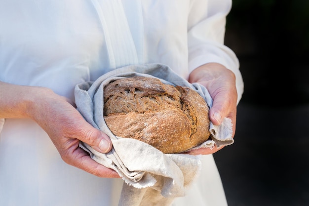 Miche fraîche de pain de seigle fait maison dans les mains de la femme