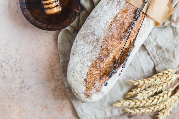 Miche de pain au levain artisanal à la lavande et au miel sur une serviette en lin avec des épis de blé