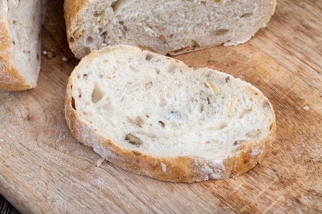 Une miche de pain de blé frais sur la table pendant la cuisson, du pain frais et moelleux aux graines de citrouille et de lin