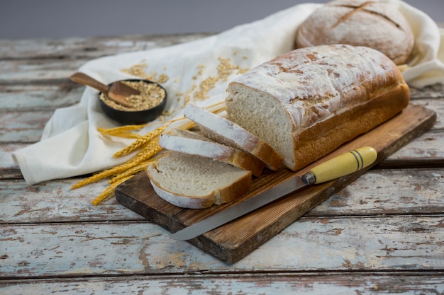 Miche de pain avec couteau, grains de blé et avoine