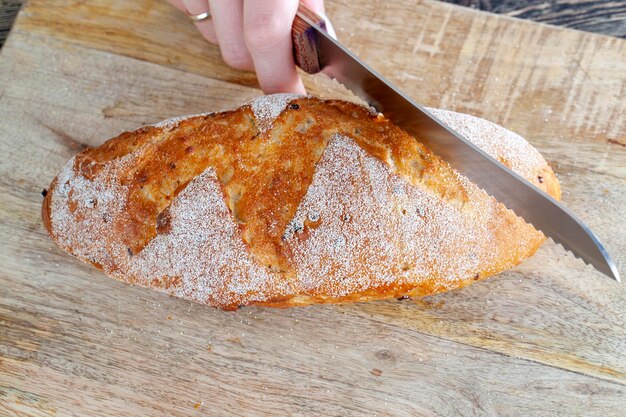 Une miche de pain frais coupé en morceaux avec un couteau