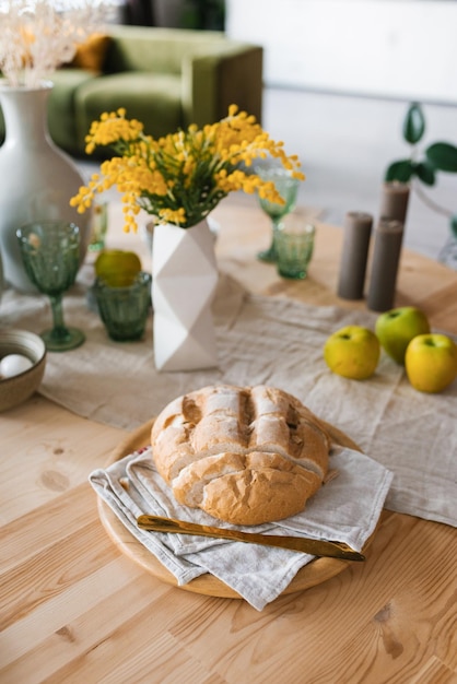 Une miche de pain frais sur la table du petit déjeuner fleurs de mimosa dans un vase