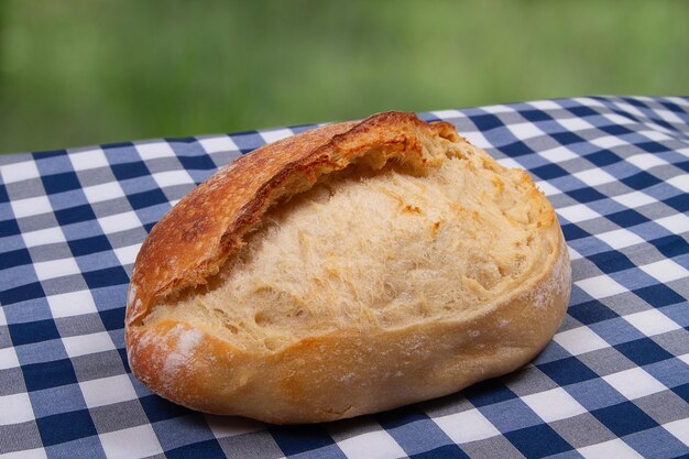 Une miche de pain français traditionnel fait maison fraîchement cuit se trouve sur la table en plein air