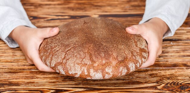 Miche de pain de seigle noir dans ses mains