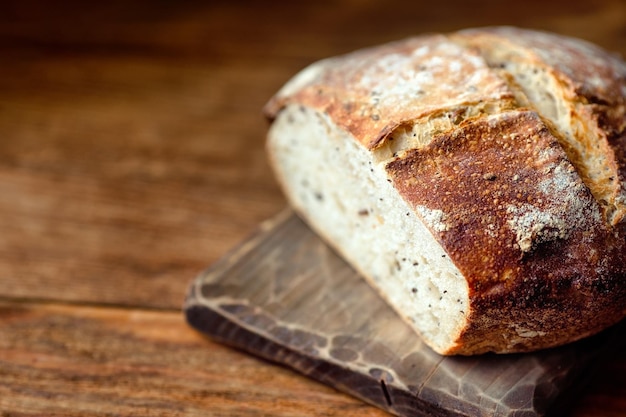 Une miche ronde de pain maison complet sans levure se trouve sur une planche de bois Des pâtisseries fraîches pour une alimentation saine