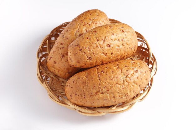 Miches de pain de blé avec des grains sur une plaque en osier sur fond blanc gros plan