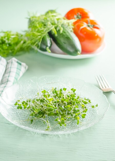 Microgreens sur plaque avec des légumes en arrière-plan, concept de régime alimentaire végétalien sain