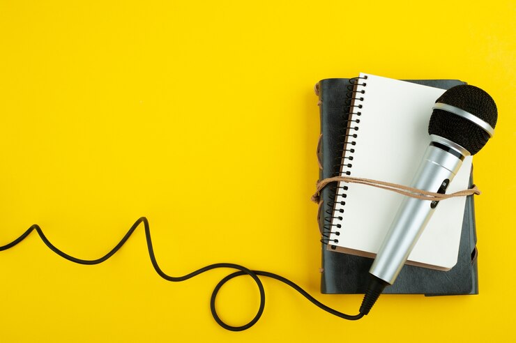 Microphone et carnet de notes ouvert vide sur papier jaune