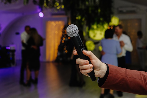 Un microphone dans une main est tenu devant un groupe de personnes qui dansent.