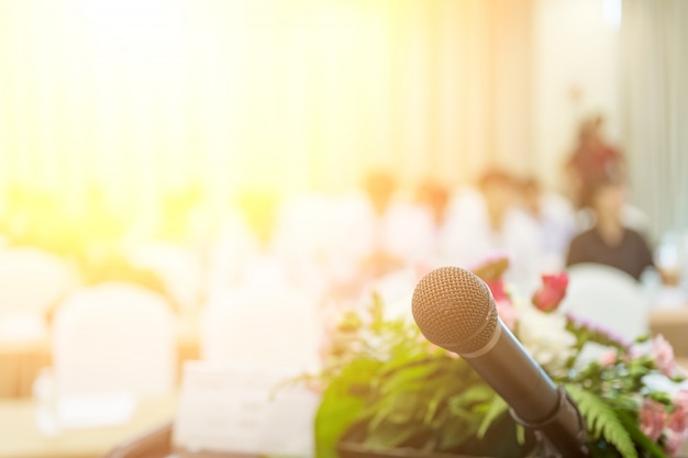 Microphone en gros plan dans une salle de séminaire ou de réunion avec des personnes floues pour la copie