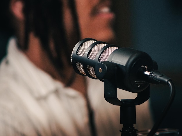 Microphone de podcast en gros plan avec une personne floue en arrière-plan