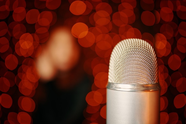 Microphone rétro sur scène et silhouette de femme en robe noire avec fond clair bokeh se bouchent avec ...