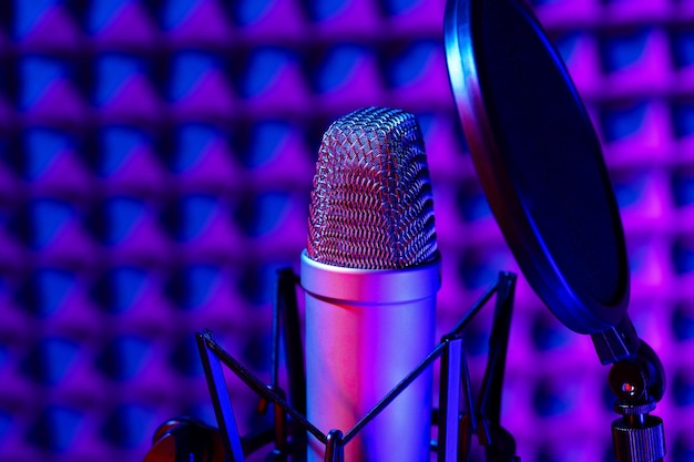 Microphone de studio professionnel contre fond de panneau en mousse acoustique à la lumière du néon