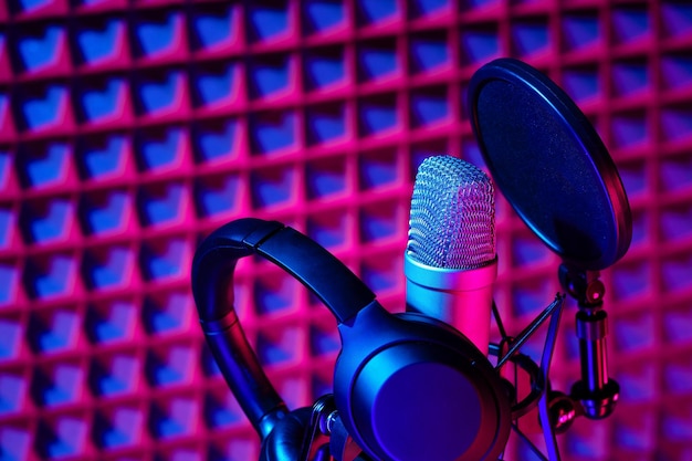 Microphone de studio professionnel contre fond de panneau en mousse acoustique à la lumière du néon