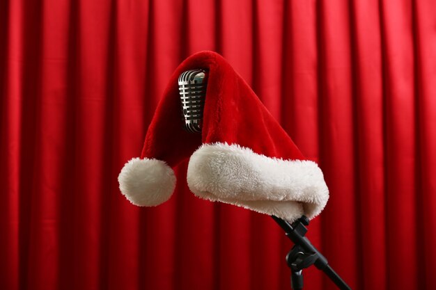 Microphone vintage avec chapeau de Noël sur fond de rideau rouge