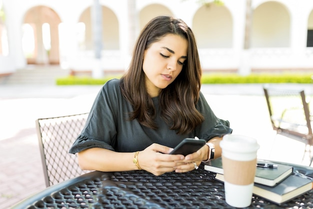 Mid adult woman checking email box sur smartphone à table dans le jardin