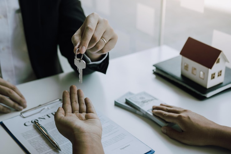 Photo midsection de l'agent donnant la clé de la maison à l'acheteur au bureau