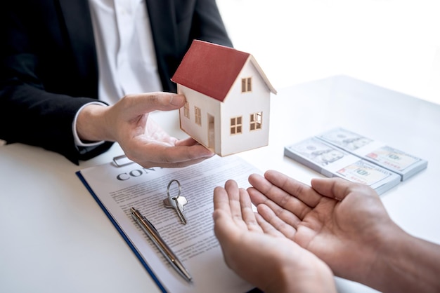 Midsection de l'agent donnant une maison modèle au client sur la table dans le bureau