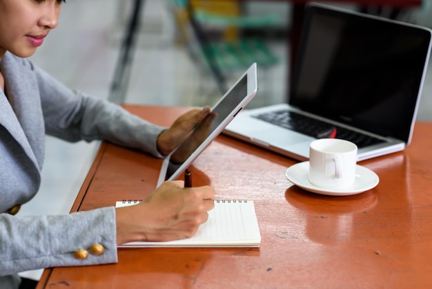 Photo midsection d'une femme d'affaires utilisant une tablette numérique tout en écrivant au bureau