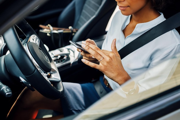 Photo midsection d'une femme utilisant un téléphone portable dans une voiture vue par la fenêtre