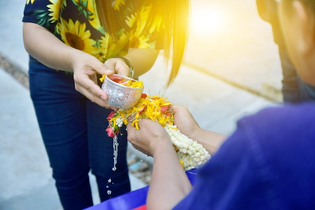 Photo midsection d'une femme versant de l'eau sur des fleurs tenues par un ami lors d'une cérémonie de mariage