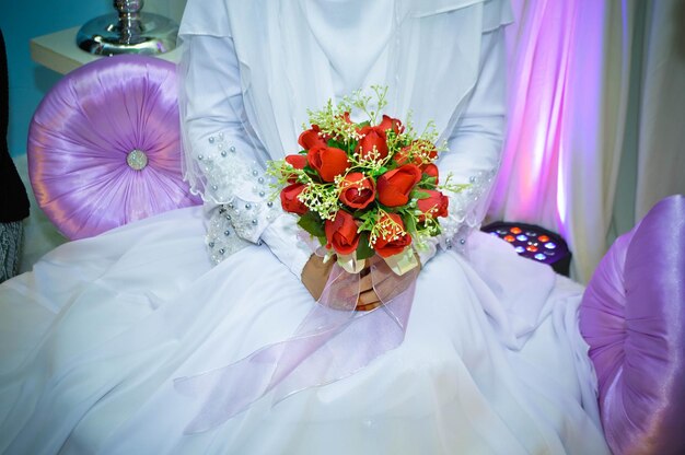 Photo midsection de la mariée tenant un bouquet de roses artificielles pendant la cérémonie de mariage