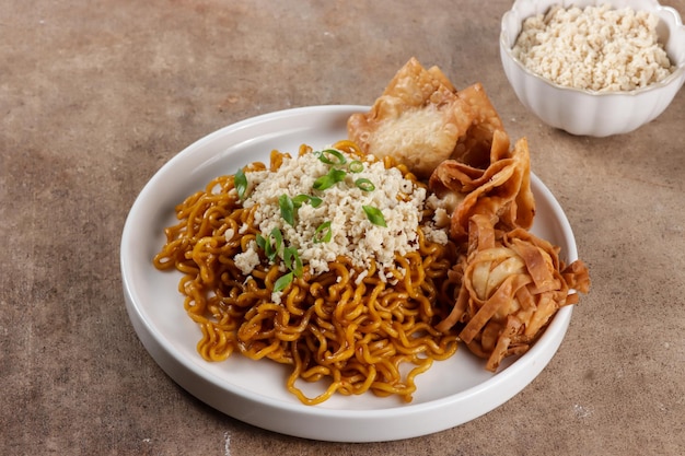 Mie Goreng ala Mie Gacoan est une garniture de nouilles frites maison avec du poulet râpé et une boulette frite.