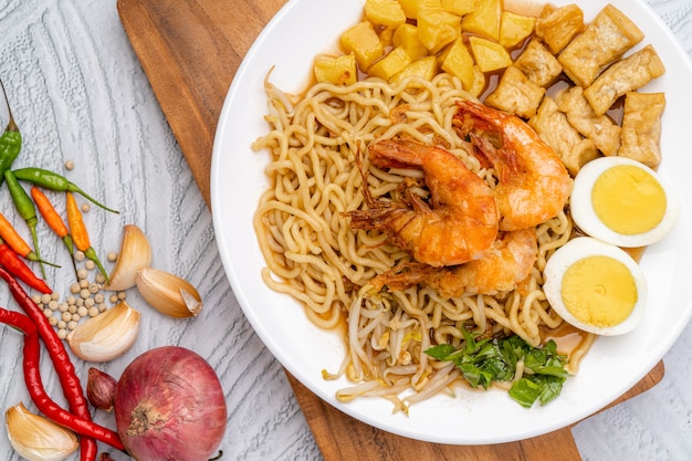 Mie rebus medan ou soupe de nouilles Le plat est composé de nouilles aux œufs jaunes qui sont également utilisées à Hokkien mee avec une sauce épicée légèrement sucrée au curry La sauce est à base de crevettes ou de bouillon de tauchu