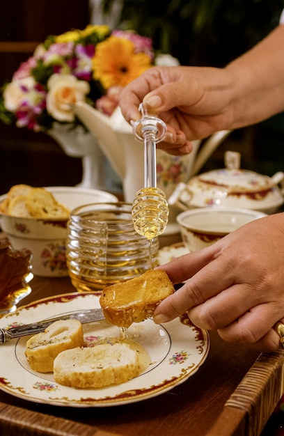 Miel d'abeille dans un récipient en verre et mains tenant du miellat sur une table dressée avec un style vintage