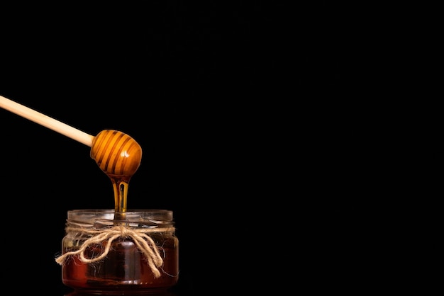 Le miel coule de la cuillère dans un bocal en verre.