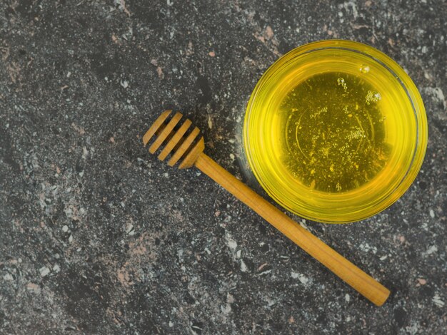 Miel dans un bol en verre avec une cuillère en bois sur une table en pierre noire Récolte fraîche de miel.