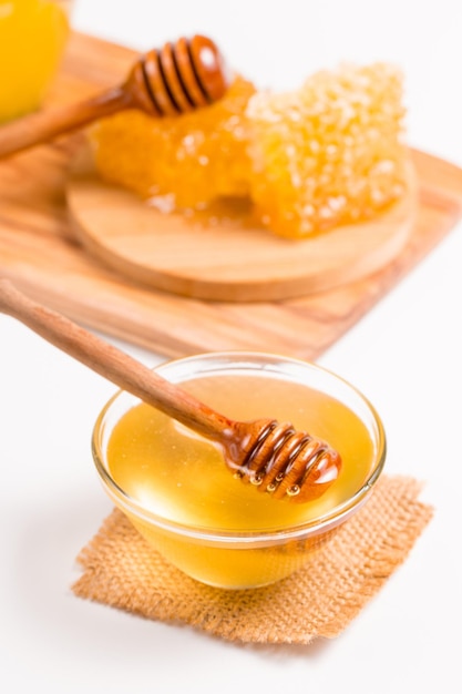 Miel dégoulinant d'une louche à miel en bois sur fond blanc. Concept d'aliments biologiques sains.