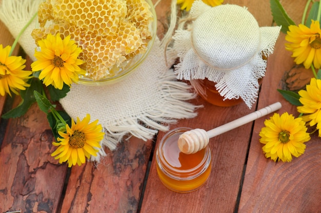 Miel doux dans le peigne Pots de nid d'abeilles sur table en bois avec fond de fleurs Vue de dessus de table