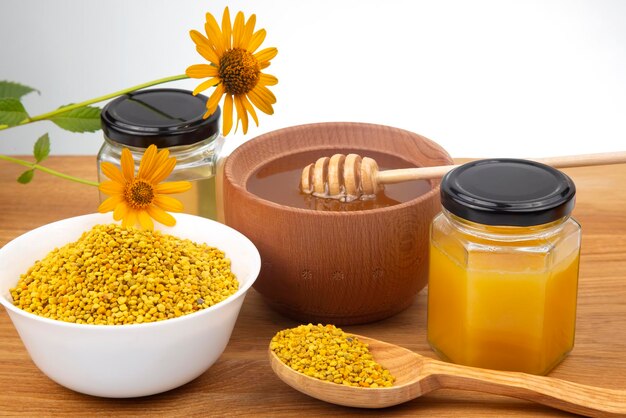 Miel de fleurs fraîches dans un bol en bois, cuillère, pollen. aliments vitaminés pour la santé et la vie