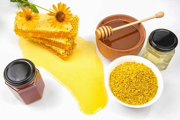 Miel de fleurs fraîches dans un bol en bois, cuillère, pollen et nid d'abeilles. aliments vitaminés pour la santé et la vie