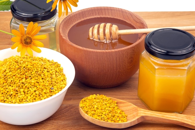 Miel de fleurs fraîches dans une cuillère à bol en bois et des aliments vitaminés en nid d'abeille pour la santé et la vie