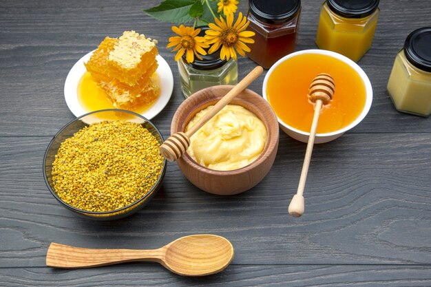 Miel de fleurs fraîches de différentes variétés, pollen et nid d'abeilles avec des cuillères sur un fond en bois. Aliments de santé aux vitamines biologiques