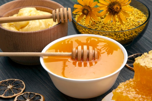 Miel de fleurs fraîches, pollen et nid d'abeilles avec des cuillères sur un fond en bois. Aliments de santé vitaminés biologiques