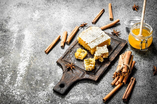 Miel frais avec des bâtons de cannelle. Sur fond rustique.