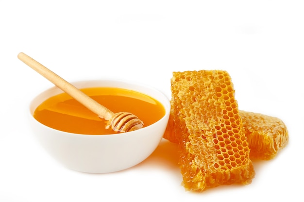 Miel frais dans un bol avec nid d'abeille isolé sur blanc. Vue de dessus