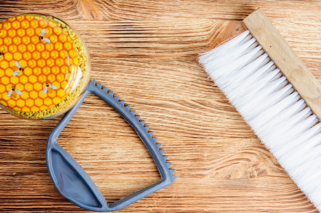 Miel frais dans le peigne et les outils de l'apiculteur sur une table en bois brun.