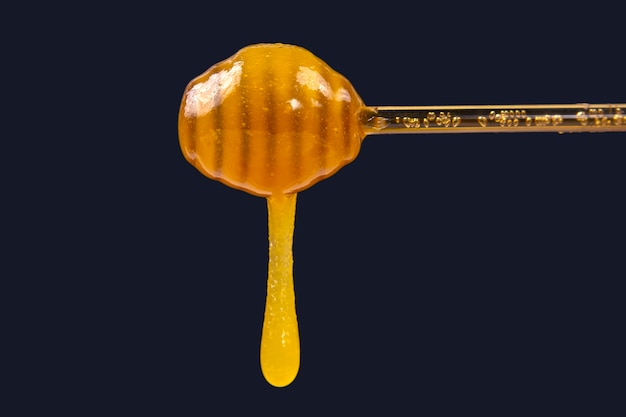 Miel frais dégoulinant d'une cuillère sur un fond sombre. aliments santé vitamines bio