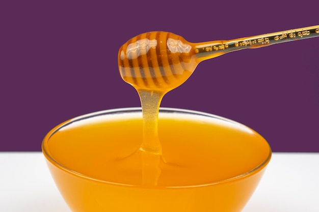 Le miel frais et parfumé coule d'une cuillère dans une assiette sur un fond coloré de vitamines bio nutrition dessert alimentaire