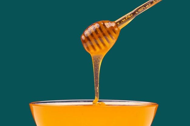 Le miel frais et parfumé coule d'une cuillère dans une assiette sur un fond coloré de vitamines bio nutrition dessert alimentaire