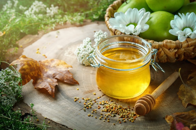 Miel frais, pollen et pommes mûres sur une table en bois