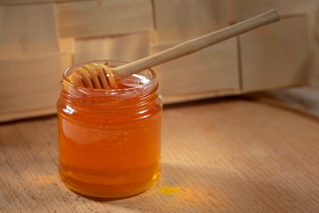 Miel liquide avec une louche de miel dans un bocal en verre sur une table en bois Miel biologique sain