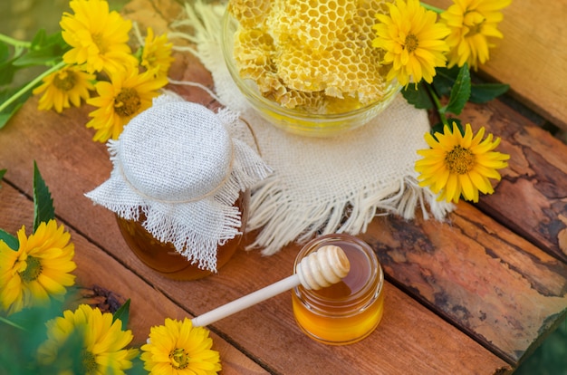 Miel avec une louche de miel sur une table en bois. Miel floral organique avec des fleurs