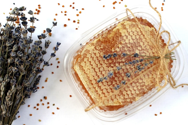 Miel en nid d'abeilles et fleurs de lavande séchées sur fond blanc