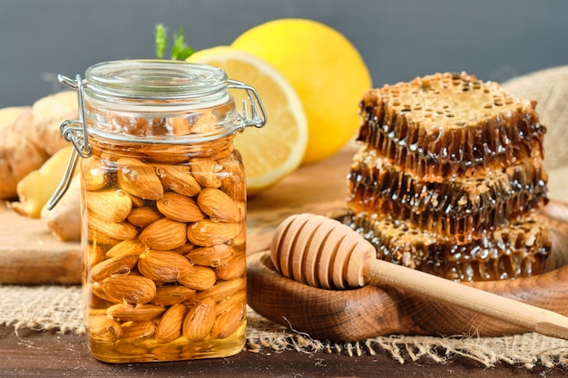 Miel en nid d'abeilles sur une plaque en bois et miel aux noix au citron et au gingembre dans un style rustique sur un espace en bois.